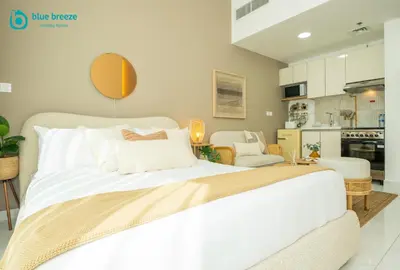 a bedroom with a large white bed and a kitchen at Blue Breeze - Elegant Studio in Serenity Lake 5, JVC in Dubai