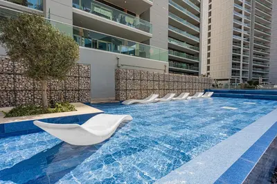 a row of white chairs sitting in a swimming pool at Apartment in Downtown Dubai in Dubai