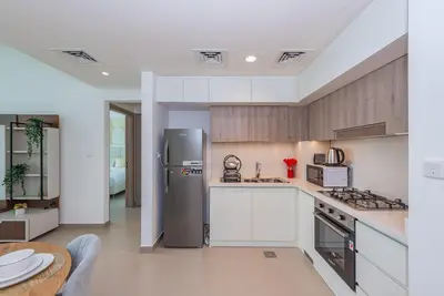 a kitchen with a stainless steel refrigerator and a table at Vayk - Spacious 1BR Apartment in Dubai Hills in Dubai