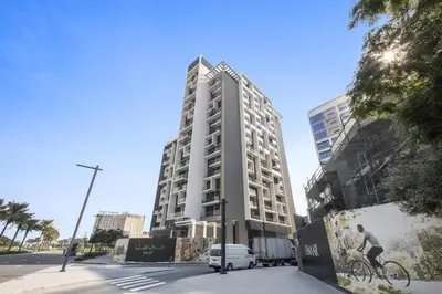 a tall building with a van parked in front of it at Vayk - Spacious 1BR Apartment in Dubai Hills in Dubai