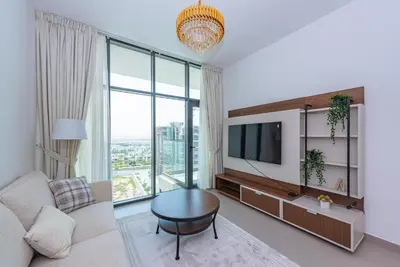 a living room with a couch and a tv at Vayk - Spacious 1BR Apartment in Dubai Hills in Dubai