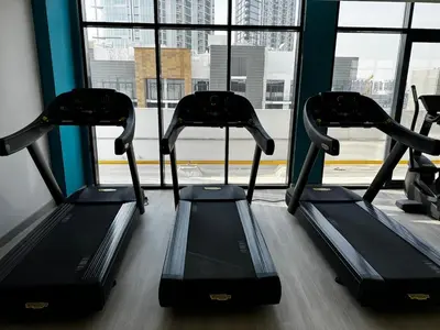 a gym with three treadmills in front of a window at Sunlit serenity Studio Azizi Riviera in Dubai