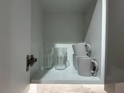 a shelf with glass vases and cups on it at Sunlit serenity Studio Azizi Riviera in Dubai