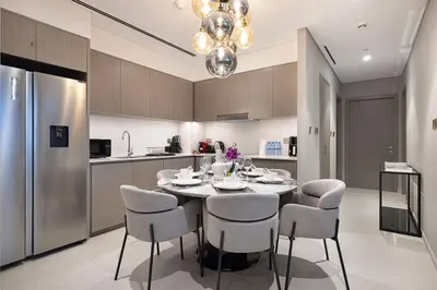 a kitchen with a table with chairs and a refrigerator at Gogoto1 Ultra LUX Burj View Spacious High Floor PS5 NYE Fireworks View in Dubai