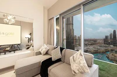 a living room with a couch and a large window at Gogoto1 Ultra LUX Burj View Spacious High Floor PS5 NYE Fireworks View in Dubai