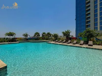 a large swimming pool with chairs and a building at Panorama Sea & Sunset View 2 BHK in Dubai
