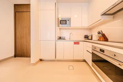 a kitchen with white cabinets and a microwave at Brand new 1BD apartment in Canal Front Residence in Dubai