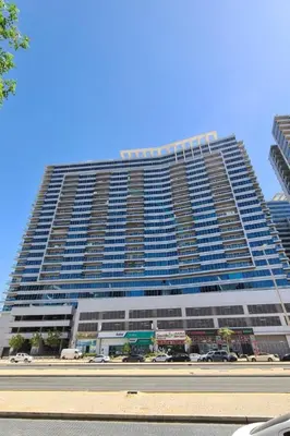 a large building with cars parked in front of it at Affordable Living 1BR, Steps from Retail Stores, Skycourts Tower D, Dubailand by Deluxe Holiday Homes in Dubai
