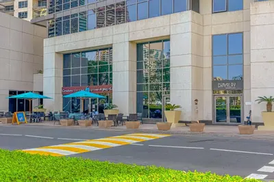a building with tables and blue umbrellas in front of it at Downtown Retreat 1BR with Skyline Views & WiFi in Dubai