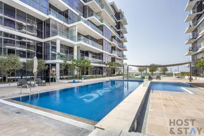 a swimming pool in front of a building at Elegant Studio Without Balcony- Damac Hills, Dubai - Host & Stay in Dubai