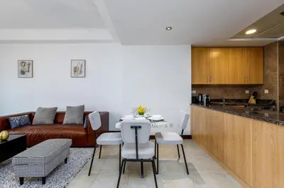 a kitchen and living room with a table and chairs at Full Lake View - 1BR Apartment in Goldcrest Views,Cluster V,JLT - Allsopp & Allsopp in Dubai