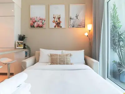 a bedroom with a large white bed and pictures on the wall at HiGuest - New! Stunning sea view studio, Balcony, Pool in Dubai