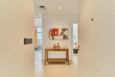 a hallway with a table and paintings on the wall at Bright & Trendy 2BR in Collective, Dubai Hills in Dubai