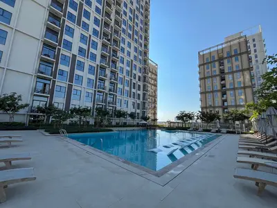 a swimming pool with chairs and tall buildings at Bright & Trendy 2BR in Collective, Dubai Hills in Dubai