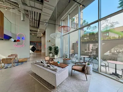 a living room with a couch and tables and windows at Bright & Trendy 2BR in Collective, Dubai Hills in Dubai