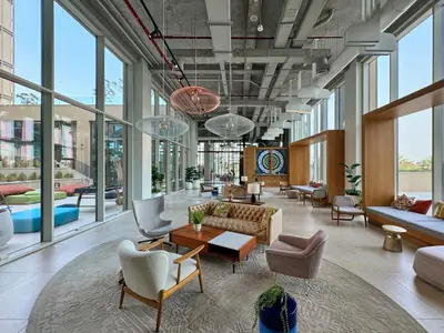a lobby with couches and chairs and windows at Bright & Trendy 2BR in Collective, Dubai Hills in Dubai
