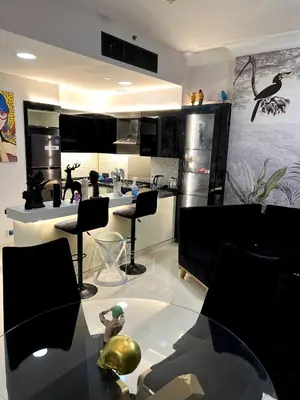 a kitchen with black cabinets and a table and chairs at 1 BR in Mall St in Dubai