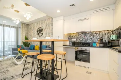 a kitchen with white cabinets and bar stools at Classic Canal View 2 Bhk 6pax in Dubai
