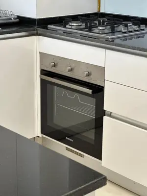 a black oven in a kitchen with white cabinets at Royal bay Azizi Palm Jumeirah in Dubai