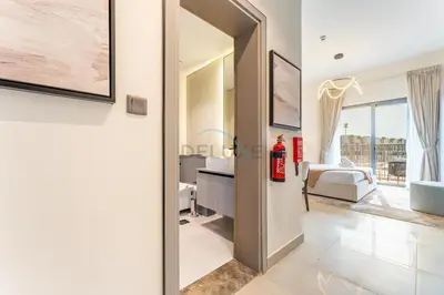a bedroom with a view of a bed and a bathroom at Community Views Studio Near Nad Al Sheba Gardens with Balcony, MAG 980, Mohammad Bin Rashid by Deluxe Holiday Homes in Dubai