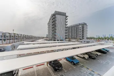 a parking lot with cars parked in front of a building at Community Views Studio Near Nad Al Sheba Gardens with Balcony, MAG 980, Mohammad Bin Rashid by Deluxe Holiday Homes in Dubai
