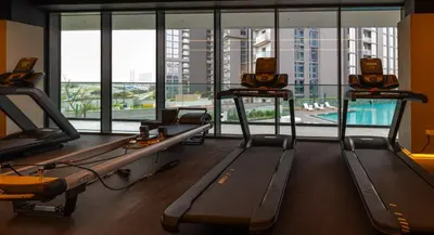 a gym with three treadmills and a large window at Premium Chic Fully Furnished 1 BR in Sobha Hartland in Dubai