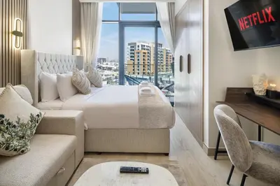 a bedroom with a bed and a couch and a window at Modern Meydan Studio Near Dubai Mall & Downtown in Dubai