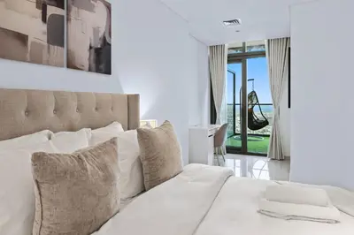 a bedroom with a white bed with a large window at PARAMOUNT MIDTOWN RESIDENCES - A Luxury 2 BR Apartment near BURJ KHALIFA and DUBAI MALL in Dubai