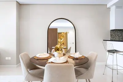 a dining room with a table and chairs and a mirror at PARAMOUNT MIDTOWN RESIDENCES - A Luxury 2 BR Apartment near BURJ KHALIFA and DUBAI MALL in Dubai