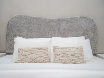 a bed with white pillows and a gray headboard at Elegant and Spacious 2-Bedroom Apartment in JVT in Dubai