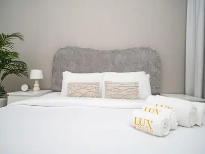 a white bed with white pillows and a gray headboard at Elegant and Spacious 2-Bedroom Apartment in JVT in Dubai