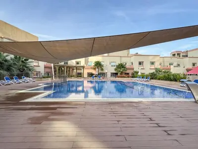 a swimming pool with chairs and a large umbrella at Elegant and Spacious 2-Bedroom Apartment in JVT in Dubai