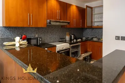 a kitchen with wooden cabinets and a granite counter top at Central Park Towers Royal suite DIFC Downtown in Dubai