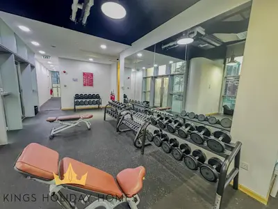a gym with a row of benches and dumbbells at Central Park Towers Royal suite DIFC Downtown in Dubai