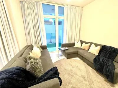a living room with a gray couch and a window at Amazing 3BHK Townhouse in Damac Hills 2 upto 10PLL in Dubai
