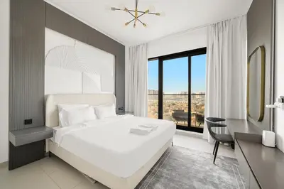 a bedroom with a white bed and a desk and a window at FIRST CLASS 1BR Stylish Urban Retreat in Dubai
