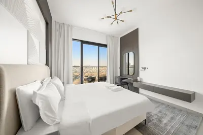a white bedroom with a large bed and a window at FIRST CLASS 1BR Stylish Urban Retreat in Dubai