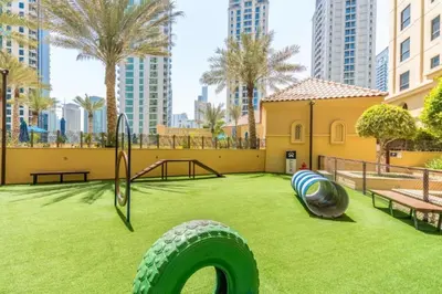 a playground with a large tire on the grass at 1BR Apartment JBR in Dubai
