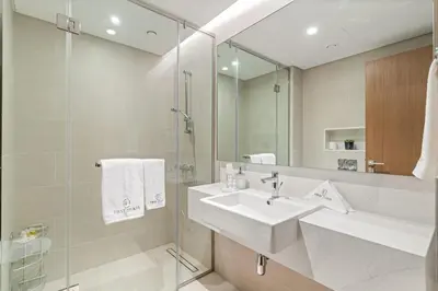 a white bathroom with a sink and a mirror at Elegant 1BR Apt with Balcony Views of Burj Khalifa & Dubai Canal in Dubai