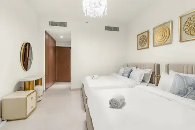 two beds in a room with white walls at Elegant 1BR Apt with Balcony Views of Burj Khalifa & Dubai Canal in Dubai