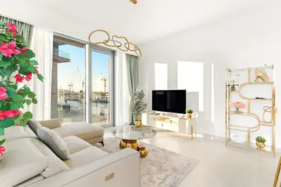 a white living room with a white couch and a tv at Elegant 1BR Apt with Balcony Views of Burj Khalifa & Dubai Canal in Dubai