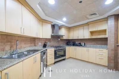 a large kitchen with wooden cabinets and stainless steel appliances at LUX The Shoreline Palm Island Skyline Suite 2 in Dubai