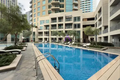 a large swimming pool with chairs and buildings at Modern 1BR in Burj Views Tower Downtown in Dubai