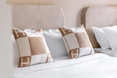 a bed with white pillows and a headboard with two pillows at Luxury 4BR with Hermes Touch & Burj Khalifa View in Dubai