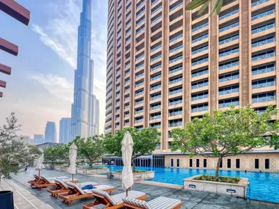 a swimming pool with chaise lounge chairs and buildings at Luxury Studio in Emaar Residence Fashion Avenue in Dubai