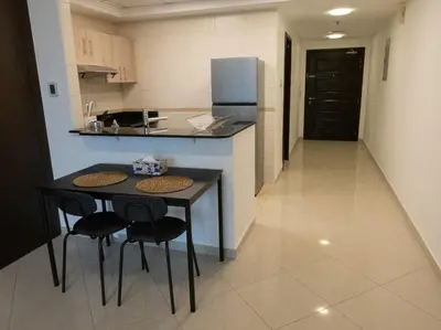 a kitchen with a table and two chairs and a refrigerator at Bright studio with new furniture in Dubai