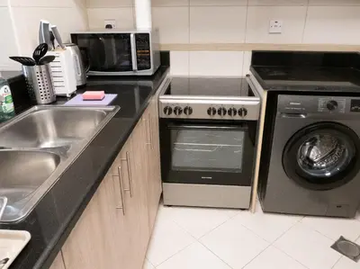 a kitchen with a sink and a washing machine at Bright studio with new furniture in Dubai