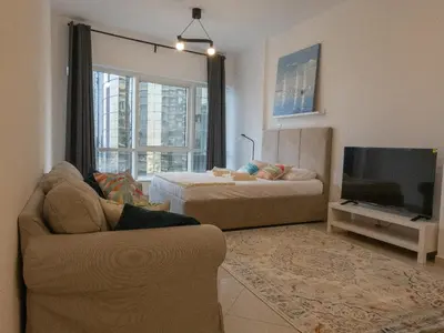 a living room with a couch and a bed and a television at Bright studio with new furniture in Dubai