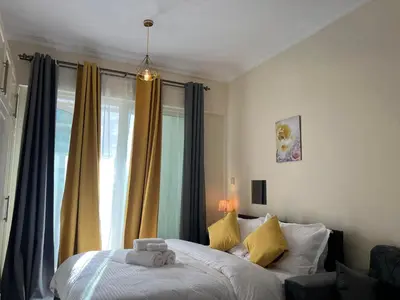 a bedroom with a bed with yellow curtains and a window at MarinaBliss in Dubai