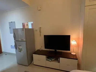 a television sitting on a cabinet next to a refrigerator at MarinaBliss in Dubai